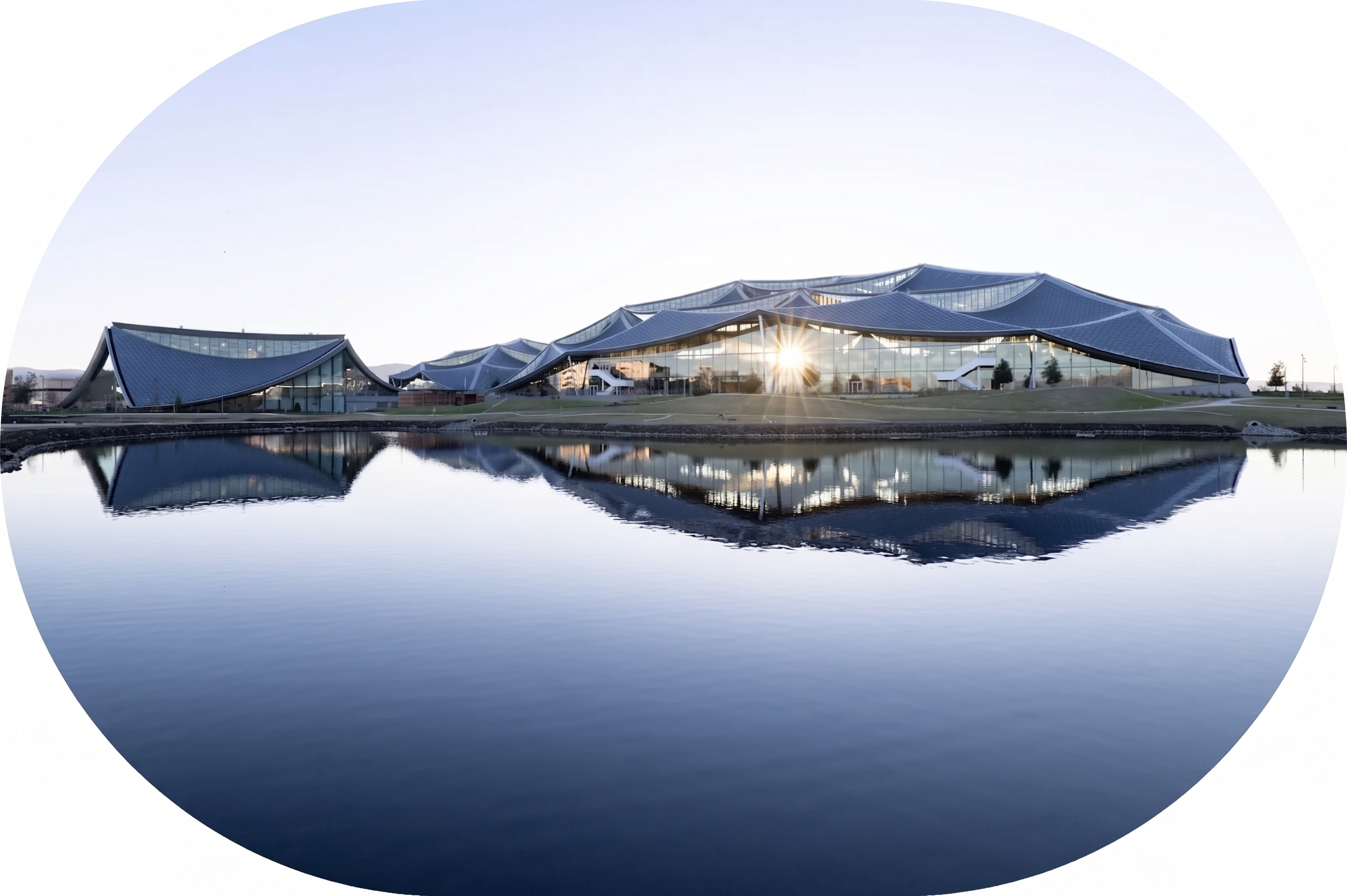 Modern building with undulating canopy roofs reflected in a calm lake as the sun shines through the glass.